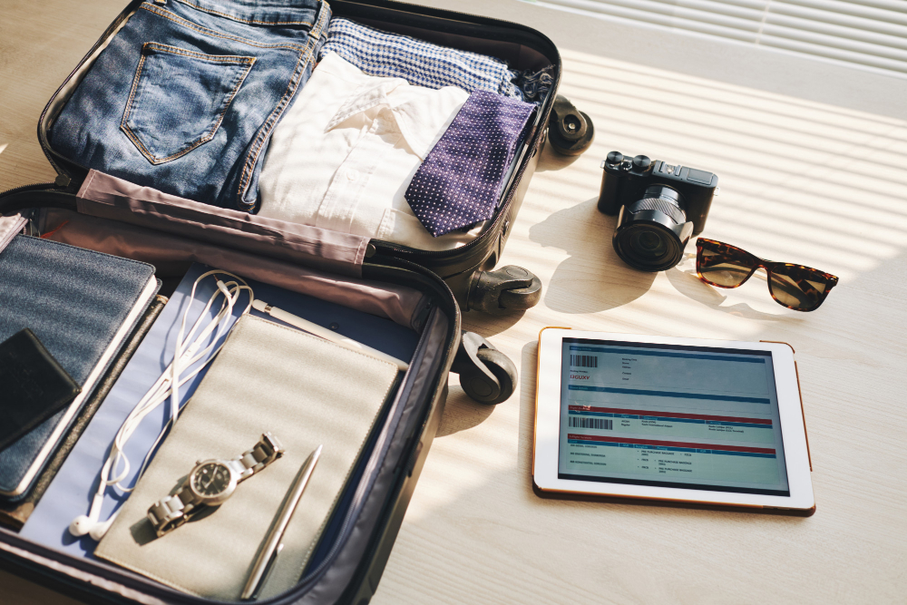Packed luggage with clothes and gadgets