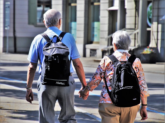 Elderly couple with backpacks holding hands