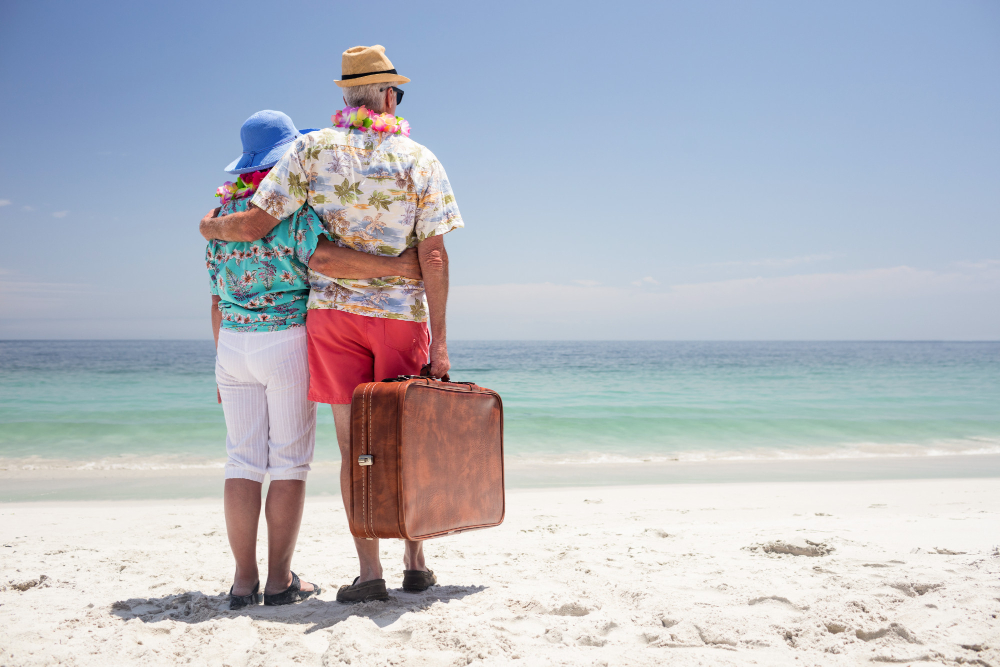 Senior couple by the sea holding a luggage