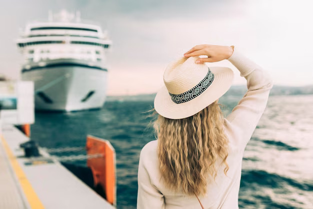 Woman holding her hat in front of a docked ship