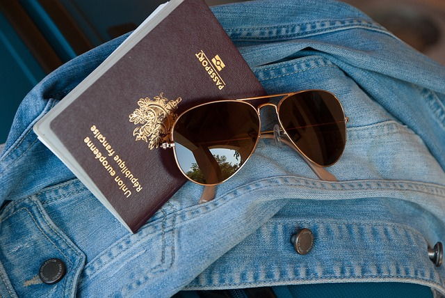 passport with sunglasses on top of a denim jacket