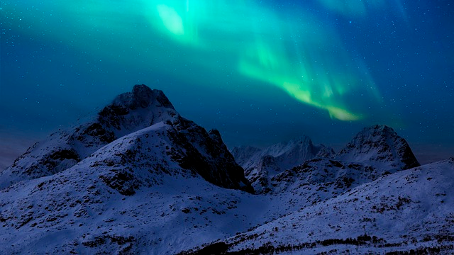 aurora borealis on top of snowy mountains at night