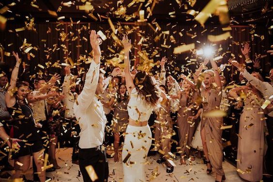 couple dancing in the middle of a crowd with confetti
