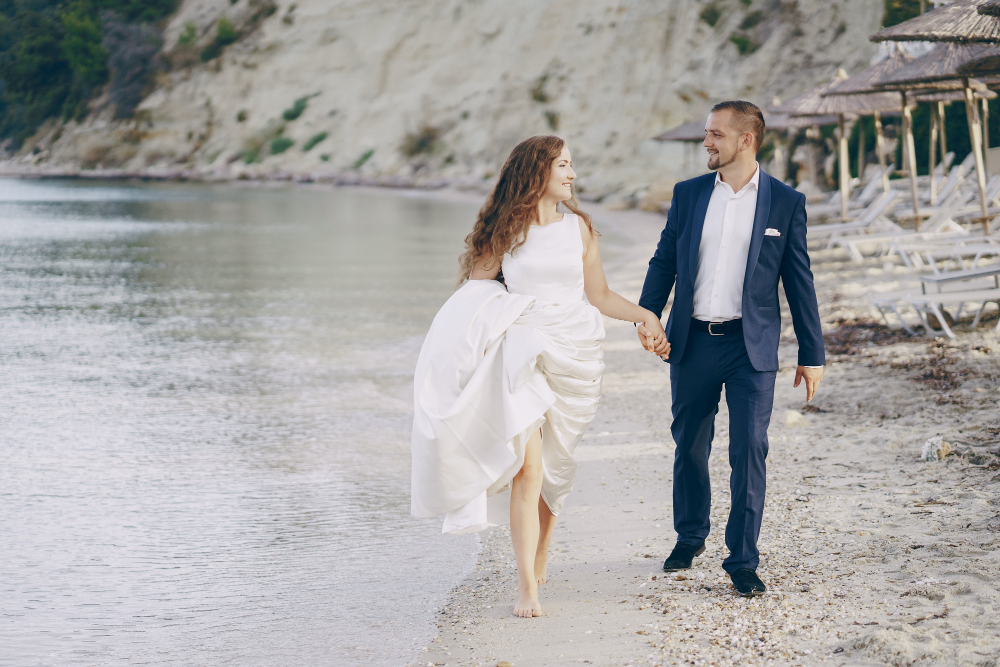 couple walking on the beach in a wedding outfit