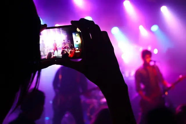 girl taking a video of the band playing