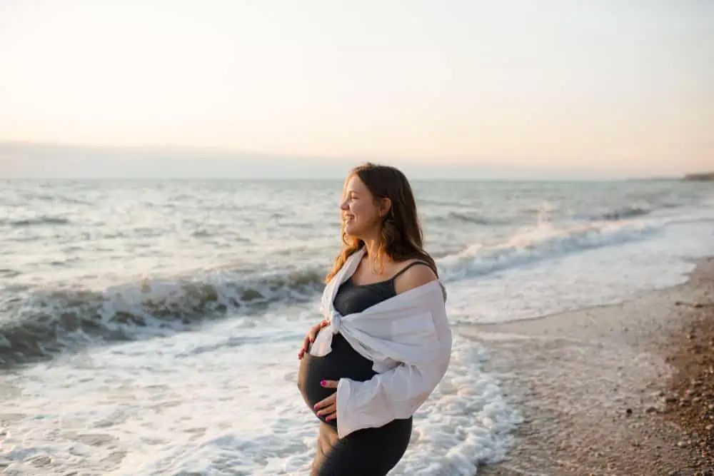 happy pregnant woman looking at the ocean