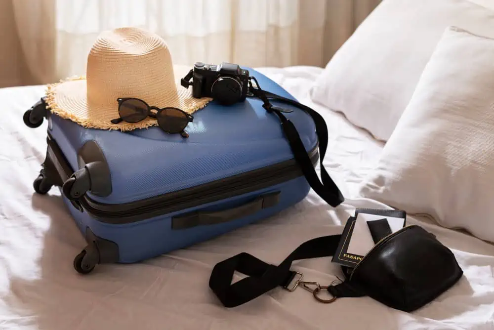 luggage on top of a bed with travel essentials