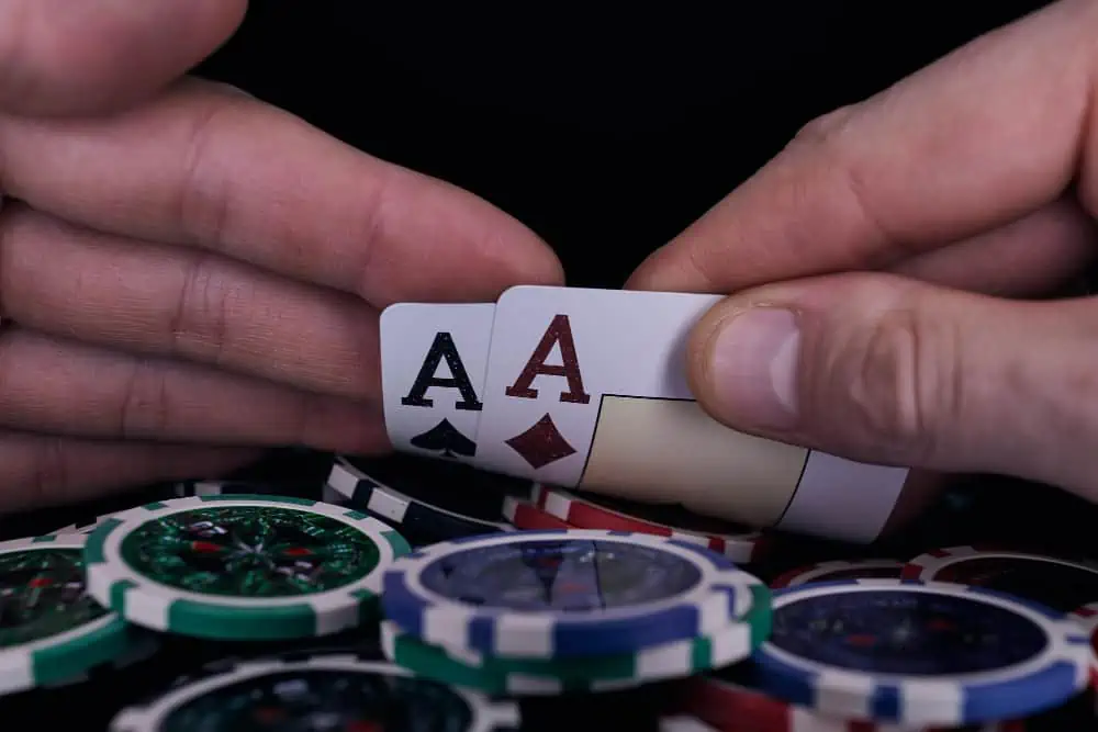 poker chips and a hand holding two aces