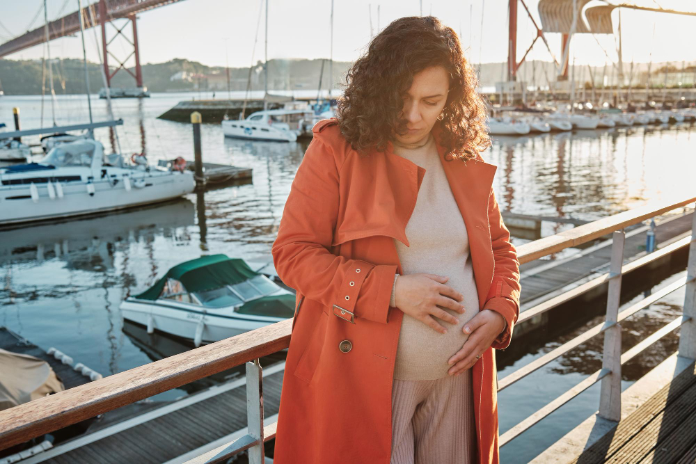 pregnant woman in an orange coat by the docks