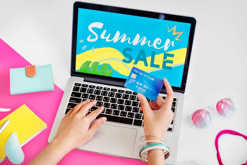 woman booking an online summer sale holding a card
