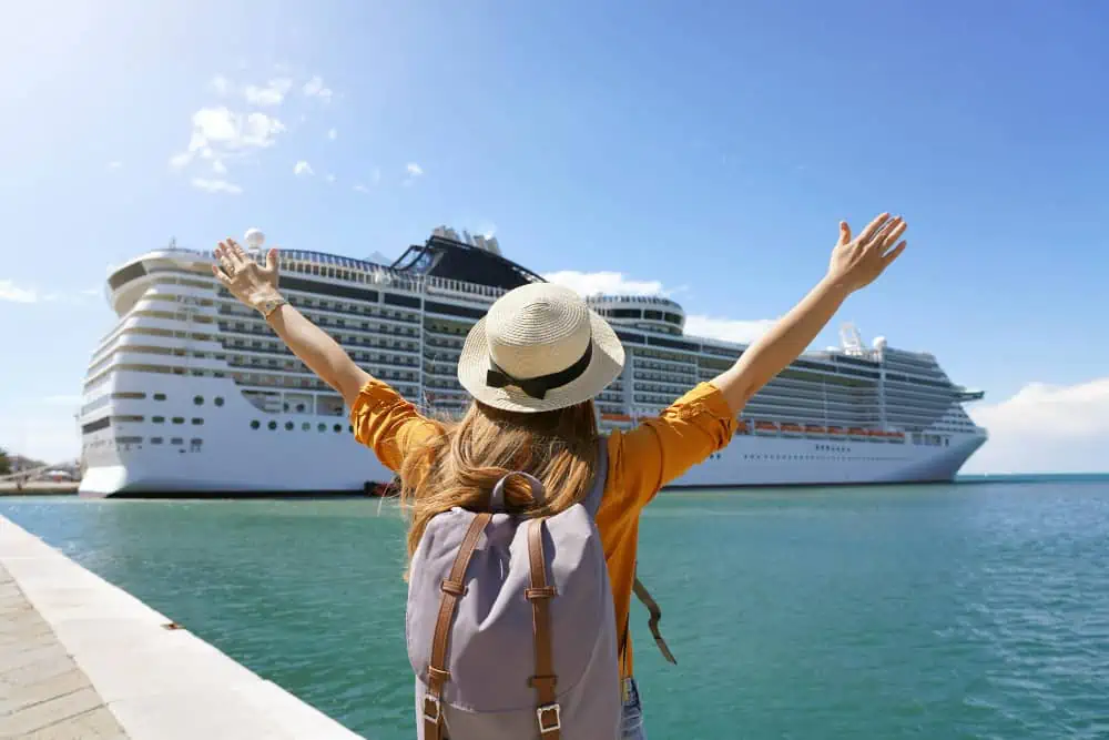 woman traveler with her hands up to a cruise ship